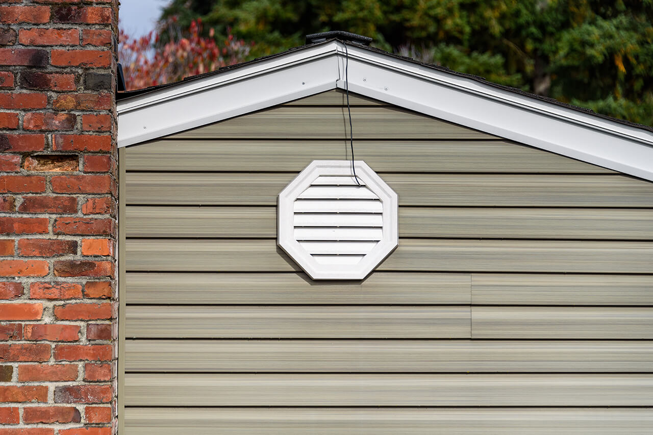 exterior attic fan vent on home near roof line