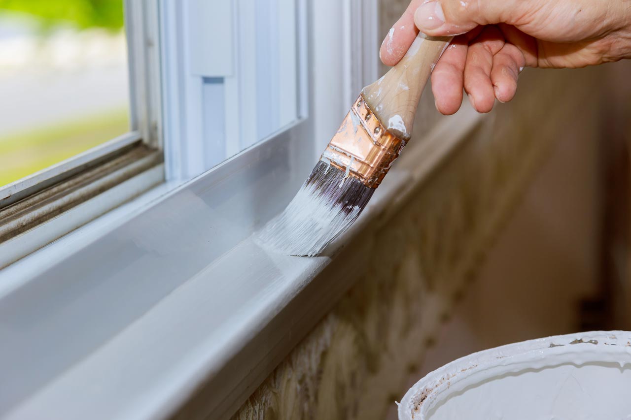 A hand painting with a brush a window trim